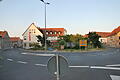 Staatsstraße und Kreisstraße treffen aufeinander. Dazwischen befindet sich die geplante Verkehrsinsel des Einbahnrings. Der Blick fällt direkt auf die Stelle, an der der Dorfbrunnen entstehen soll.