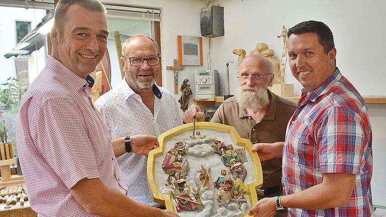 Mario Sitzmann, Vorsitzender der Kirchenverwaltung, Bürgermeister Martin Schmitt (links) und Burkard Geißler, Vorsitzender des Pfarrgemeinderates bei der Übergabe des neuen Vierzehnheiligenbildes. Der Milzer Schnitzer Dieter Frank (rechts hinten) zeigt die besonderen Feinheiten seines Kunstwerks.