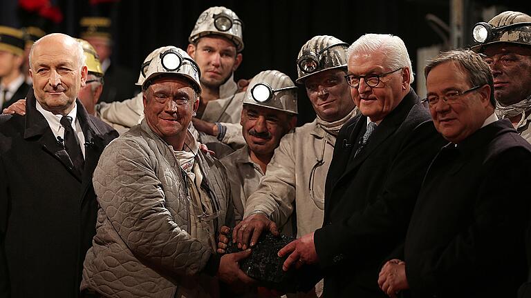 Peter Schrimpf, Vorstandsvorsitzender der Ruhrkohle AG (links), Bundespräsident Frank-Walter Steinmeier (Zweiter v. rechts) und Armin Laschet (rechts, CDU), NRW-Ministerpräsident stehen mit Bergleuten und dem letzten Stück Steinkohle vor dem Schacht auf der Zeche Prosper Haniel. Mit der symbolischen Förderung des letzten Stücks Kohle ist der Steinkohlebergbau beendet worden.&nbsp;