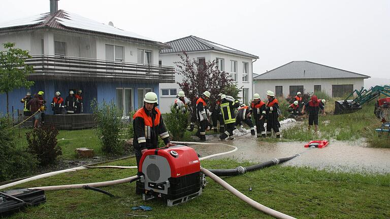 Am Sonntagmorgen überflutete Wasser, das aus den angrenzenden Feldern in die Siedlung "Am Steinbruch" in Mönchstockheim floss, mehrere Anwesen. Feuerwehrleute pumpten Wasser ab und bauten einen Damm aus Brettern, Sandsäcken und Erde. Am Sonntagmorgen überflutete Wasser, das aus den angrenzenden Feldern in die Siedlung "Am Steinbruch" in Mönchstockheim floss, mehrere Anwesen. Feuerwehrleute pumpten Wasser ab und bauten einen Damm aus Brettern, Sandsäcken und Erde.