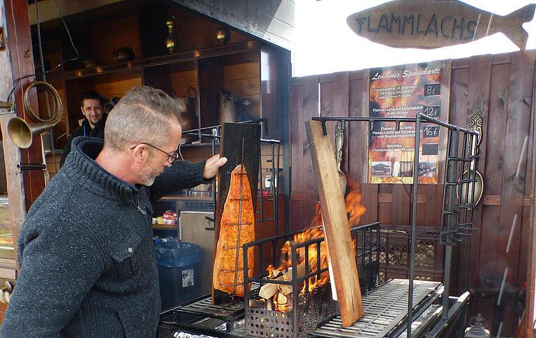 Flammlachs: Ein Händler bestreicht hingebungsvoll Lachsteile am offenen Feuer.