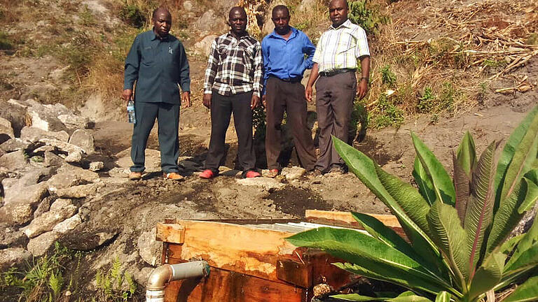 Das Wasserprojekt im Mkoha wird von den Dipbachern unterstützt. Die Quelle hoch auf dem Berg ist schon gefasst. Von links: Bischof John Ndimbo, zwei Arbeiter an der Wasserleitung und Father Orestes aus Mkoha.