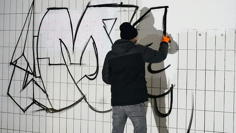 Einige Stunden Arbeit nahm das große Graffiti an der zuvor noch kargen Wand in Anspruch. Zunächst wurde die Schrift mit schwarzer Sprühfarbe gesprayt und anschließend mit bunten Neonfarben ausgefüllt. Einige Stunden Arbeit nahm das große Graffiti an der zuvor noch kargen Wand in Anspruch. Zunächst wurde die Schrift mit schwarzer Sprühfarbe gesprayt und anschließend mit bunten Neonfarben ausgefüllt.