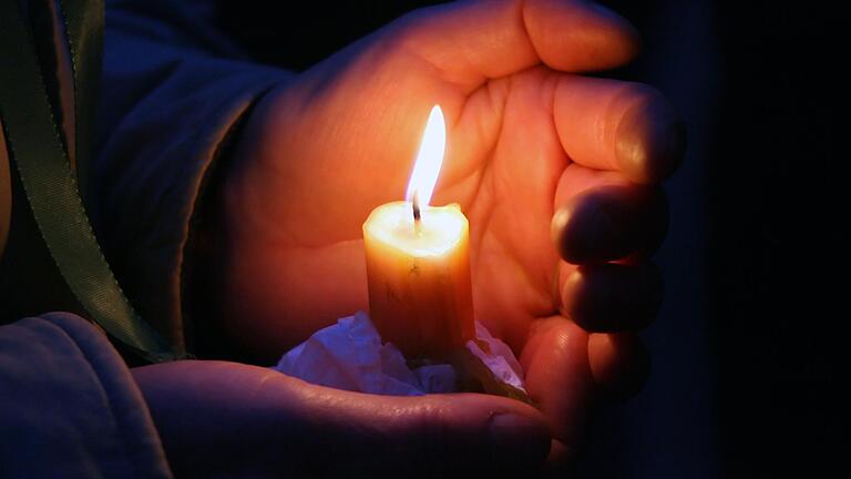 Schützend bewahrt die Hand einer Passantin eine Kerze vor dem Wind bei an der Leipziger Nikolaikirche (Symbolbild). Zu einer Mahnwache für den Frieden in Europa laden die Stadtführer Marco Schmitt und Johann Giglhuber am Donnerstag, 17. Februar, um 18 Uhr nach Bad Neustadt ein.