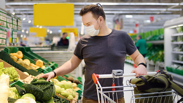 Man wearing disposable medical mask shopping in supermarket during coronavirus pneumonia outbreak       -  Trotz strenger Hygieneregeln steht die Eigenverantwortung zu Corona-Zeiten im Mittelpunkt. Besonders beim Einkaufen.
