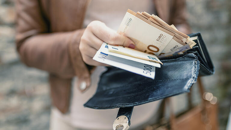 Woman holding in hands wallet with euro money. City girl is taking out money from wallet       -  Symbolbild: Geld