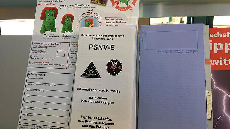 Schriftenstand im Foyer des Gerätehauses der Kitzinger Feuerwehr: Ein Flyer weist auf Angebote der Psychosozialen Notfallversorgung (PSNV) hin, die Einsatzkräfte nach einem besonders belastenden Ereignissen unterstützen.