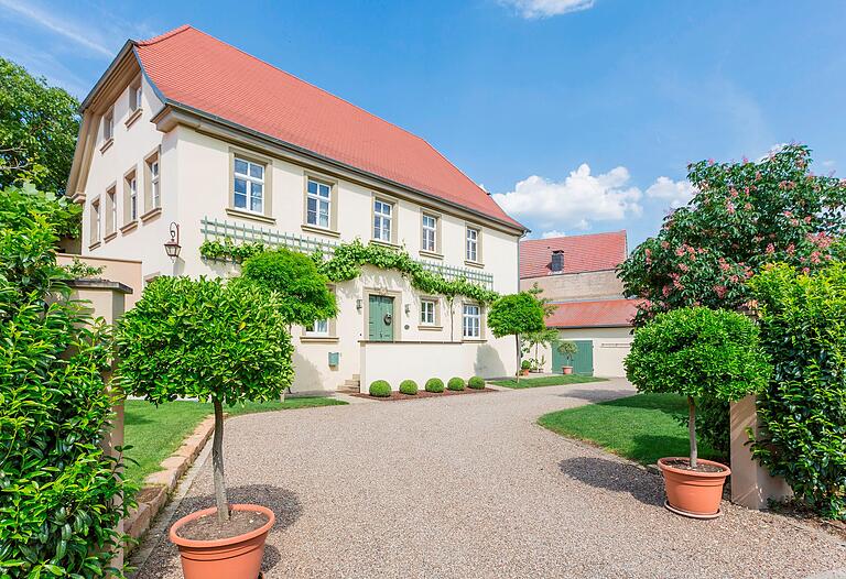 Ein regionaltypisches Haus in Kolitzheim, dessen Fassade durch Natursteinrahmungen von Fenstern und Türen, durch Fensterteilungen und durch Fassadengrün gegliedert ist. Ein regionaltypisches Haus in Kolitzheim, dessen Fassade durch Natursteinrahmungen von Fenstern und Türen, durch Fensterteilungen und durch Fassadengrün gegliedert ist.