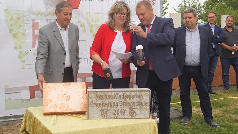 Vorsichtig schlugen Thomas Eberth, Bürgermeister von Kürnach (rechts) und dessen Amtskollegin Birgit Börger auf den Grundstein, während Kürnachs dritter Bürgermeister Edgar Kamm den Metallkasten hält, der hinter dem Grundstein eingemauert wird und aktuelle Informationen über Kürnach und eine Ausgabe der Main-Post vom Tag der Grundsteinlegung enthält.