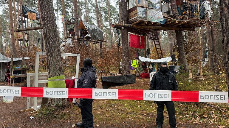 Polizei-Einsatz im Tesla-Protestcamp in Grünheide       -  Polizeikräfte sichern das Waldgebiet hinter einer Absperrung. Umweltaktivisten, die gegen Tesla protestieren, müssen ihr Camp räumen.