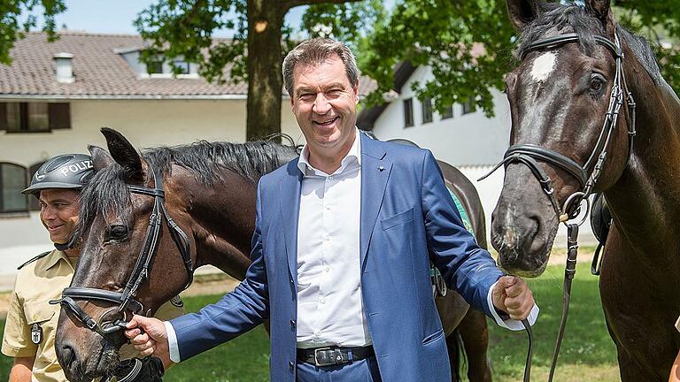 Ministerpräsident Söder besucht Polizei-Reiterstaffel - Ministerpräsident Markus Söder (CSU) hält bei der Reiterstaffel des Polizeipräsidiums München das Zaumzeug zweier Polizeipferde. Ministerpräsident Söder besucht Polizei-Reiterstaffel - Ministerpräsident Markus Söder (CSU) hält bei der Reiterstaffel des Polizeipräsidiums München das Zaumzeug zweier Polizeipferde.