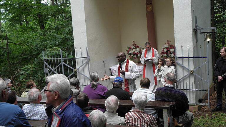 Pfarrvikar Bede Nwadinobi (links) bei seiner Predigt vor der Sodenbergkapelle, hinter ihm Pater Marek Sobkowiak und Ministranten.