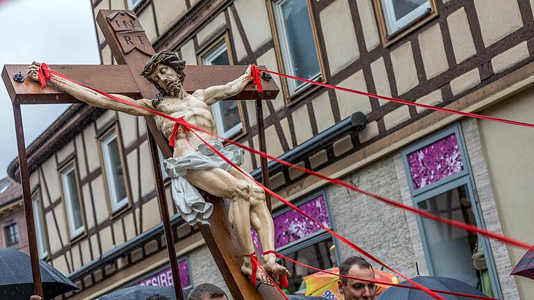 Rote Stoffbänder symbolisieren die 'Gnadenströme' und gehen von den Wunden des Gekreuzigten aus. Sie machen das Kreuz zu einer der eindrucksvollsten Figuren in der Karfreitagsprozession. Rote Stoffbänder symbolisieren die 'Gnadenströme' und gehen von den Wunden des Gekreuzigten aus. Sie machen das Kreuz zu einer der eindrucksvollsten Figuren in der Karfreitagsprozession.