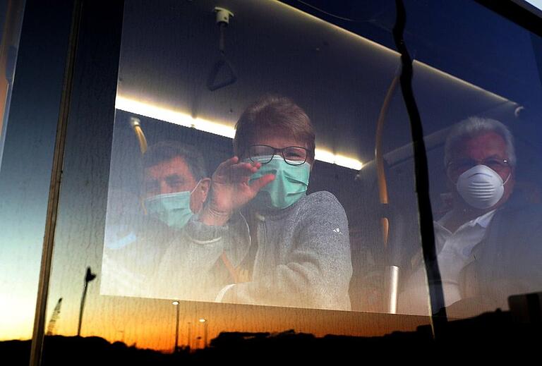 Erleichtert: Mit Mundschutz versehen werden die Passagiere der MS „Artania“ mit Bussen zum Flughafen gefahren. Erleichtert: Mit Mundschutz versehen werden die Passagiere der MS „Artania“ mit Bussen zum Flughafen gefahren.