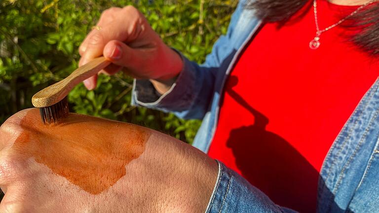 Monika zeigt, wie das Drachenblut, das in Ecuador auch 'Amazonas-Pflaster' genannt wird, nach dem Auftragen seine Textur verändert. Nach einer Zeit wird es fast cremig, bevor es schließlich ganz glatt wird und wie eine zweite Haut Wunden verschließt.