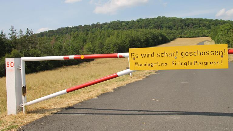 Schranke mit Schild 'Es wird scharf geschossen'&nbsp;im Truppenübungsplatz Hammelburg. Dahinter der Berg, auf dessen Spitze die Ruine Reußenburg steht.