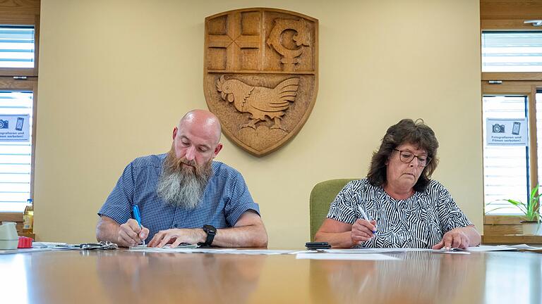 Vor dem Wappen der Gemeinde Üchtelhausen: Schriftführerin Margot Schraub und Abstimmungsvorstand Georg Metzger.