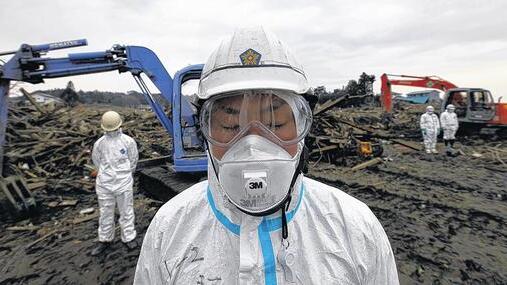 Trauer und Entsetzen: Polizisten in Schutzkleidung, die in der Provinz Fukushima nach Leichen suchen, verharren während einer Schweigeminute für die Opfer des Erdbebens und des Tsunamis in Stille. Trauer und Entsetzen: Polizisten in Schutzkleidung, die in der Provinz Fukushima nach Leichen suchen, verharren während einer Schweigeminute für die Opfer des Erdbebens und des Tsunamis in Stille.