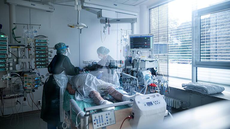 Symbolbild: Mitarbeiterinnen der Pflege in Schutzausrüstung betreut einen Corona-Patienten.