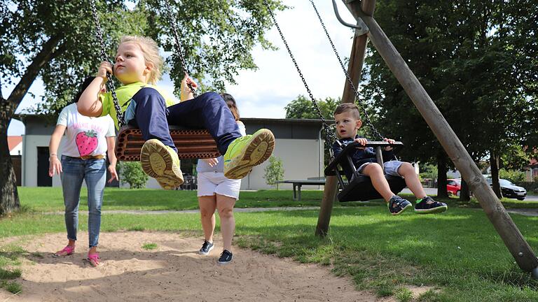 Spielplatz Buchbrunn: Die Kinder schaukeln, während sich die Mütter unterhalten. Und der Dorfladen im Hintergrund hat sogar eine Terrasse, auf der man Kaffee und Kuchen genießen kann. Spielplatz Buchbrunn: Die Kinder schaukeln, während sich die Mütter unterhalten. Und der Dorfladen im Hintergrund hat sogar eine Terrasse, auf der man Kaffee und Kuchen genießen kann.