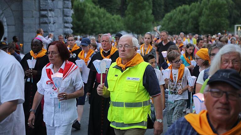 Erkennungszeichen orangenes Tuch: der Arzt Georg Lippert bei der Lichterprozession in Lourdes. Im Hintergrund Bischof Friedhelm Hofmann. Erkennungszeichen orangenes Tuch: der Arzt Georg Lippert bei der Lichterprozession in Lourdes. Im Hintergrund Bischof Friedhelm Hofmann.