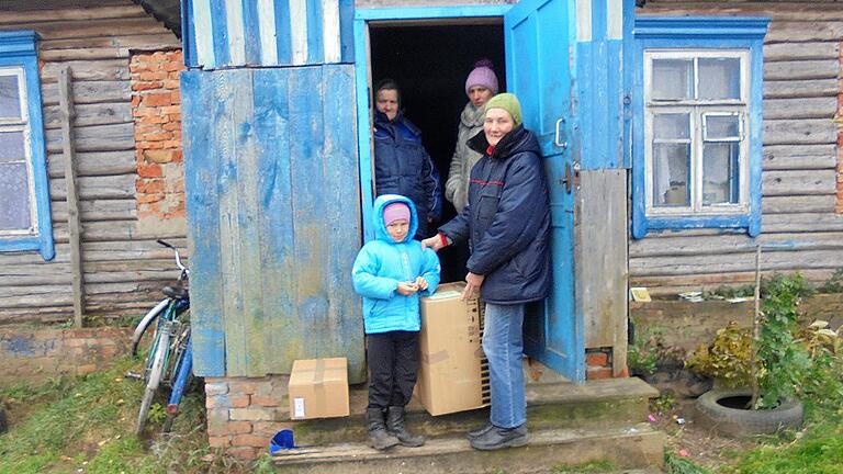 Eine arme Familie aus dem Dorf Chwoika beim Empfang eines Kleider- und eines Lebensmittelpaketes.