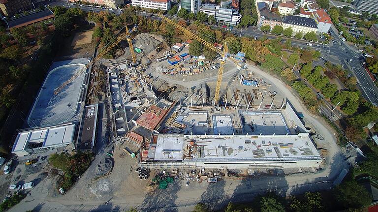 Diese Luftbildaufnahme des Nautiland-Nachfolgebades entstand Ende August: Links im Bild die Eisbahn als Oval und direkt daran angrenzend der Sauna-Trakt des künftigen Bades; in der Mitte Eingang und Gastronomie (rot), rechts das Schwimmbad. Der weiße Teil unten ist der Umkleidebereich. Daran angrenzend die drei Schwimmbecken im Innern des Bades, und wiederum angrenzend der Außenbereich. Wo der gelbe Kran steht, befindet sich mittlerweile der Treppenturm für die künftige Riesenrutsche. Sie führt in das Becken direkt vor dem Kran. Diese Luftbildaufnahme des Nautiland-Nachfolgebades entstand Ende August: Links im Bild die Eisbahn als Oval und direkt daran angrenzend der Sauna-Trakt des künftigen Bades; in der Mitte Eingang und Gastronomie (rot), rechts das Schwimmbad. Der weiße Teil unten ist der Umkleidebereich. Daran angrenzend die drei Schwimmbecken im Innern des Bades, und wiederum angrenzend der Außenbereich. Wo der gelbe Kran steht, befindet sich mittlerweile der Treppenturm für die künftige Riesenrutsche. Sie führt in das Becken direkt vor dem Kran. 