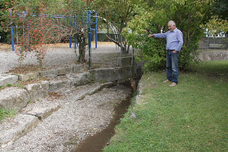 Anlieger Herbert Liebler zeigt auf die Stelle am Spielplatz, wo kaum noch Wasser im Bachbett fließt. Wegen der großen Menge Kies, die dort liegt, können seiner Meinung nach keine Forellen mehr dort schwimmen. Anlieger Herbert Liebler zeigt auf die Stelle am Spielplatz, wo kaum noch Wasser im Bachbett fließt. Wegen der großen Menge Kies, die dort liegt, können seiner Meinung nach keine Forellen mehr dort schwimmen.