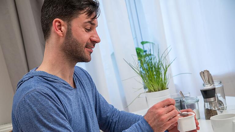 Ein Mann isst einen Pudding       -  High-Protein-Puddings bieten viel Eiweiß, doch natürliche Alternativen wie Magerquark oder Vollkornbrot mit Hummus liefern die gleiche Menge Protein ohne Zusatzstoffe.