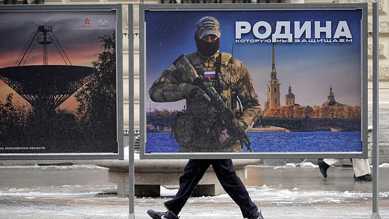 Ukraine-Krieg - Härtere Strafen für Kritik an russ       -  Ein Mann geht in Moskau an einem Plakat mit dem Bild eines russischen Soldaten und der Aufschrift 'Wir verteidigen das Vaterland' vorbei .