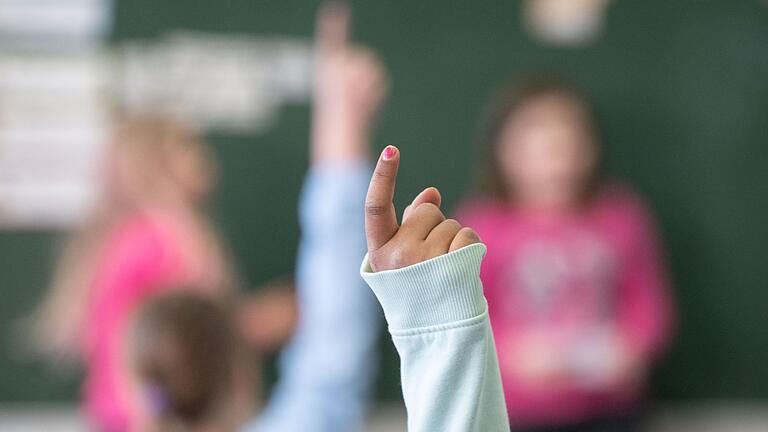 Schule       -  Eine Schülerin meldet sich im Unterricht.