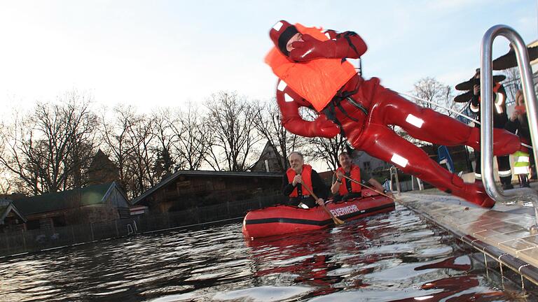 Ein Feuerwehrmann im Überlebensanzug springt ins Becken des Gerolzhöfer Freibads. Mit Hilfe des Anzugs können Menschen im Wasser schnell erreicht und vor dem Untergehen bewahrt werden.