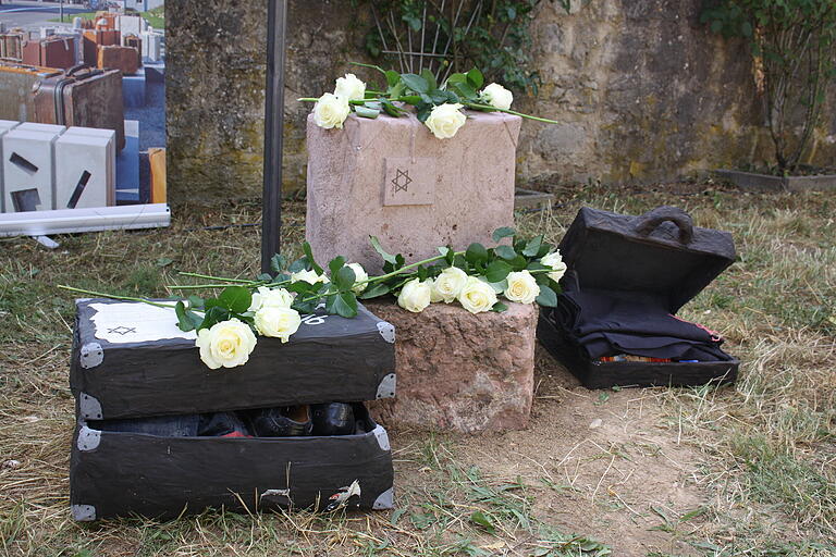 Bei der Aufstellung der Gepäckstücke zur Erinnerung und Mahnung an die Deportation wurden weiße Rosen auf den sandsteinernen Koffer und die Vorlagen aus dem Kunstunterricht gelegt. Bei der Aufstellung der Gepäckstücke zur Erinnerung und Mahnung an die Deportation wurden weiße Rosen auf den sandsteinernen Koffer und die Vorlagen aus dem Kunstunterricht gelegt.
