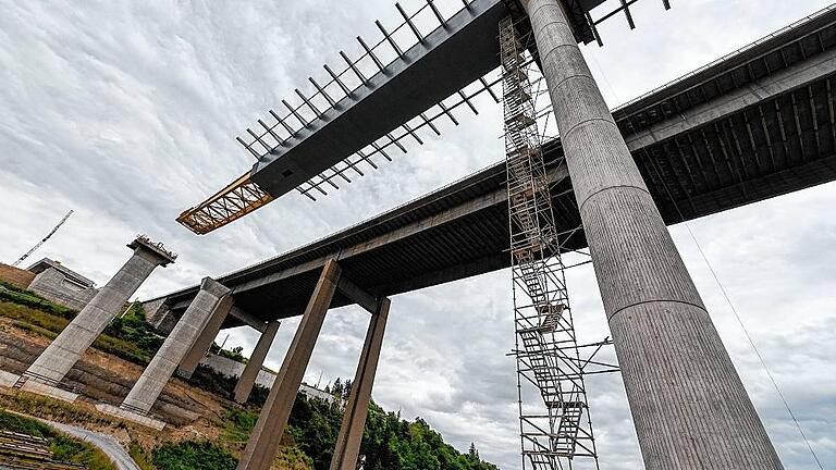 Noch ein Teil fehlt zum Brückenschluss bei Heidingsfeld - (ella) Es geht weiter voran. Seit Montagmorgen läuft der nächste Verschub der neuen Heidingsfelder Talbrücke im Zuge des A 3-Ausbaus. Im Gegensatz zu der Brückenbaustelle bei Schraudenbach, bei deren Einsturz vor kurzem ein Mensch starb, werden in Würzburg die Elemente zwischen den Pfeilern nicht aus Beton gegossen, sondern aus Stahlplatten zusammengeschweißt und dann über das Tal geschoben. Der mittlerweile fünfte Abschnitt, der noch bis Dienstagnachmittag in Richtung Widerlager Katzenbergtunnel verschoben wird, hat eine Länge von 119 Metern und wiegt 808 Tonnen, informiert Wolfgang Thaler, Losbauführer bei der Autobahndirektion Nordbayern. Wenn das Brückenteil seinen Endpunkt erreicht hat, sind 572 Meter und 4855 Tonnen Stahlüberbau der späteren Brücke montiert. Dann fehlen nur noch 70 Meter bis zum Erreichen des Widerlagers am Radweg zum Heuchelhof. Dies soll Ende Juli geschehen, so Thaler weiter. Daran anschließend folgt das Auflegen von Fertigteilen als „Schalung“ sowie das Aufbringen einer Stahlbetonschicht auf die Stahlelemente von 30 Zentimetern Stärke. Das sind laut Thaler etwa 3000 Kubikmeter Beton. Dies soll im Laufe des Sommers 2016 erfolgen, daran anschließend folgt die Erstellung der Bauwerkskappen, der Lärmschutzwand, der Abdichtung und des Belags, gleichzeitig laufen die Fertigstellung von Tunnel und Tunnelausstattung mit der komplexen Tunneltechnik. So könne laut Thaler voraussichtlich Ende 2017 die nördliche Fahrbahn in Betrieb gehen. Der sogenannte Vorbauschnabel, das gelbe Anbaustück, kommt nach dem Verschub mittig über der Heuchelhofstraße, in etwa über der Gleisanlage der Straßenbahn, zu liegen, informiert Thaler. Dazu seien Sicherheitsvorkehrungen getroffen und abgestimmt, um den Verkehr zu schützen. Noch ein Teil fehlt zum Brückenschluss bei Heidingsfeld - (ella) Es geht weiter voran. Seit Montagmorgen läuft der nächste Verschub der neuen Heidingsfelder Talbrücke im Zuge des A 3-Ausbaus. Im Gegensatz zu der Brückenbaustelle bei Schraudenbach, bei deren Einsturz vor kurzem ein Mensch starb, werden in Würzburg die Elemente zwischen den Pfeilern nicht aus Beton gegossen, sondern aus Stahlplatten zusammengeschweißt und dann über das Tal geschoben. Der mittlerweile fünfte Abschnitt, der noch bis Dienstagnachmittag in Richtung Widerlager Katzenbergtunnel verschoben wird, hat eine Länge von 119 Metern und wiegt 808 Tonnen, informiert Wolfgang Thaler, Losbauführer bei der Autobahndirektion Nordbayern. Wenn das Brückenteil seinen Endpunkt erreicht hat, sind 572 Meter und 4855 Tonnen Stahlüberbau der späteren Brücke montiert. Dann fehlen nur noch 70 Meter bis zum Erreichen des Widerlagers am Radweg zum Heuchelhof. Dies soll Ende Juli geschehen, so Thaler weiter. Daran anschließend folgt das Auflegen von Fertigteilen als „Schalung“ sowie das Aufbringen einer Stahlbetonschicht auf die Stahlelemente von 30 Zentimetern Stärke. Das sind laut Thaler etwa 3000 Kubikmeter Beton. Dies soll im Laufe des Sommers 2016 erfolgen, daran anschließend folgt die Erstellung der Bauwerkskappen, der Lärmschutzwand, der Abdichtung und des Belags, gleichzeitig laufen die Fertigstellung von Tunnel und Tunnelausstattung mit der komplexen Tunneltechnik. So könne laut Thaler voraussichtlich Ende 2017 die nördliche Fahrbahn in Betrieb gehen. Der sogenannte Vorbauschnabel, das gelbe Anbaustück, kommt nach dem Verschub mittig über der Heuchelhofstraße, in etwa über der Gleisanlage der Straßenbahn, zu liegen, informiert Thaler. Dazu seien Sicherheitsvorkehrungen getroffen und abgestimmt, um den Verkehr zu schützen.
