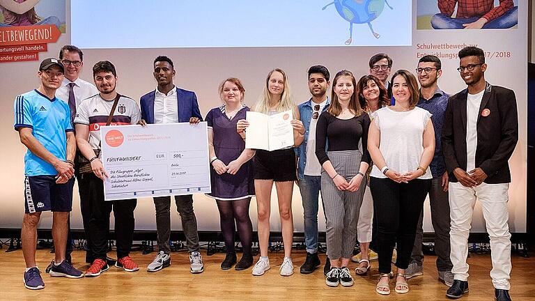 Verleihung des 3. Preises für die Filmgruppe: Preisübergabe an die Filmgruppe des Staatlichen Beruflichen Schulzentrums Alfons Goppel. Mit im Bild: Bundesentwicklungsminister Gerd Müller (Zweiter von links), Sabine Otter, Leiterin der Filmgruppe (Fünfte von rechts), Ralph Caspers, Moderator der Preisverleihung (Vierter von rechts).