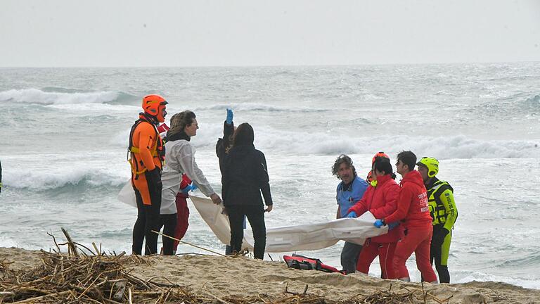 Bootsunglück vor Süditalien       -  Rettungskräfte im Einsatz am Strand in der Nähe von Cutro, Süditalien.