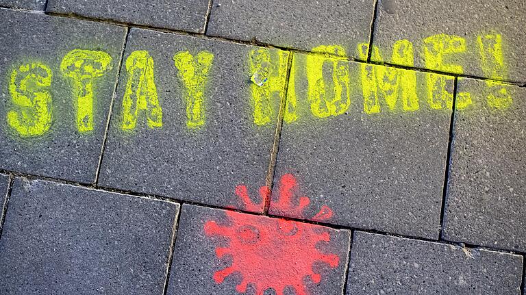 Ein Graffiti bestehend aus dem Text 'Stay Home' ('Bleibt daheim') und einer symbolischen Virusdarstellung ist in einer Fußgängerzone auf den Boden gesprüht worden. Bundesweit sollen die Schüler in den nächsten Wochen zu Hause bleiben.