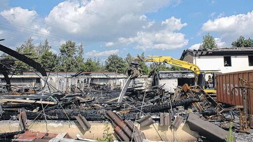 Ein Bagger nimmt die verkohlten Teile der Brandruine auf und wirft sie in einen Container. In drei Wochen soll das Bowlingcenter komplett abgebrochen sein, wie Miteigentümer Wolfgang Kunzmann berichtet.