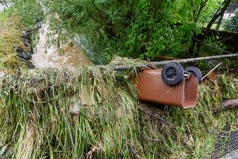 Nach dem Hochwasser vom Mai 2016: Der Heigelsbach floss am nächsten Tag wieder harmlos wirkend in seinem Bett, das Gras und die angeschwemmte Biotonne im Brückengeländer zeigen jedoch, wie hoch der Wasserstand nach dem lokalen Gewitter des Vortages gewesen war.