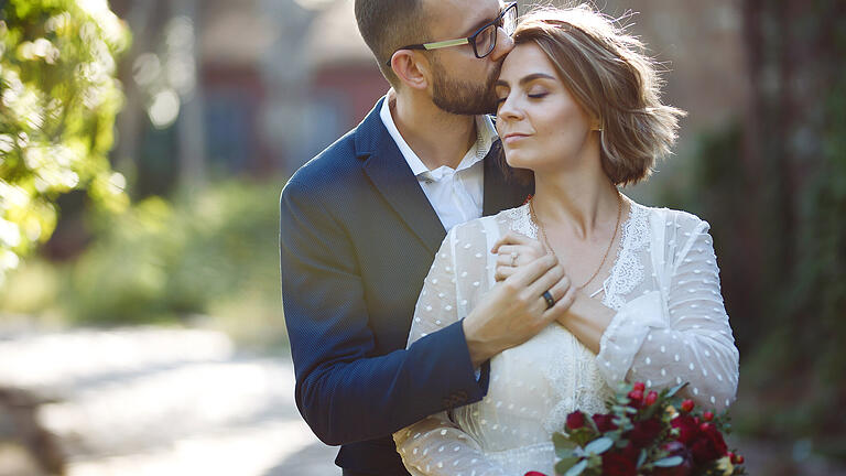 Young couple enjoying romantic moments while walking in the park in the sun.       -  In Corona-Zeiten entscheiden sich immer mehr Brautpaare für eine intime Hochzeit zu zweit.
