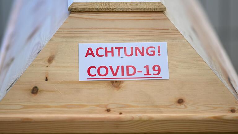 Ein Sarg mit der Aufschrift 'Achtung! Covid-19' steht in einem Raum im Krematorium, bevor der Sarg eingeäschert wird.