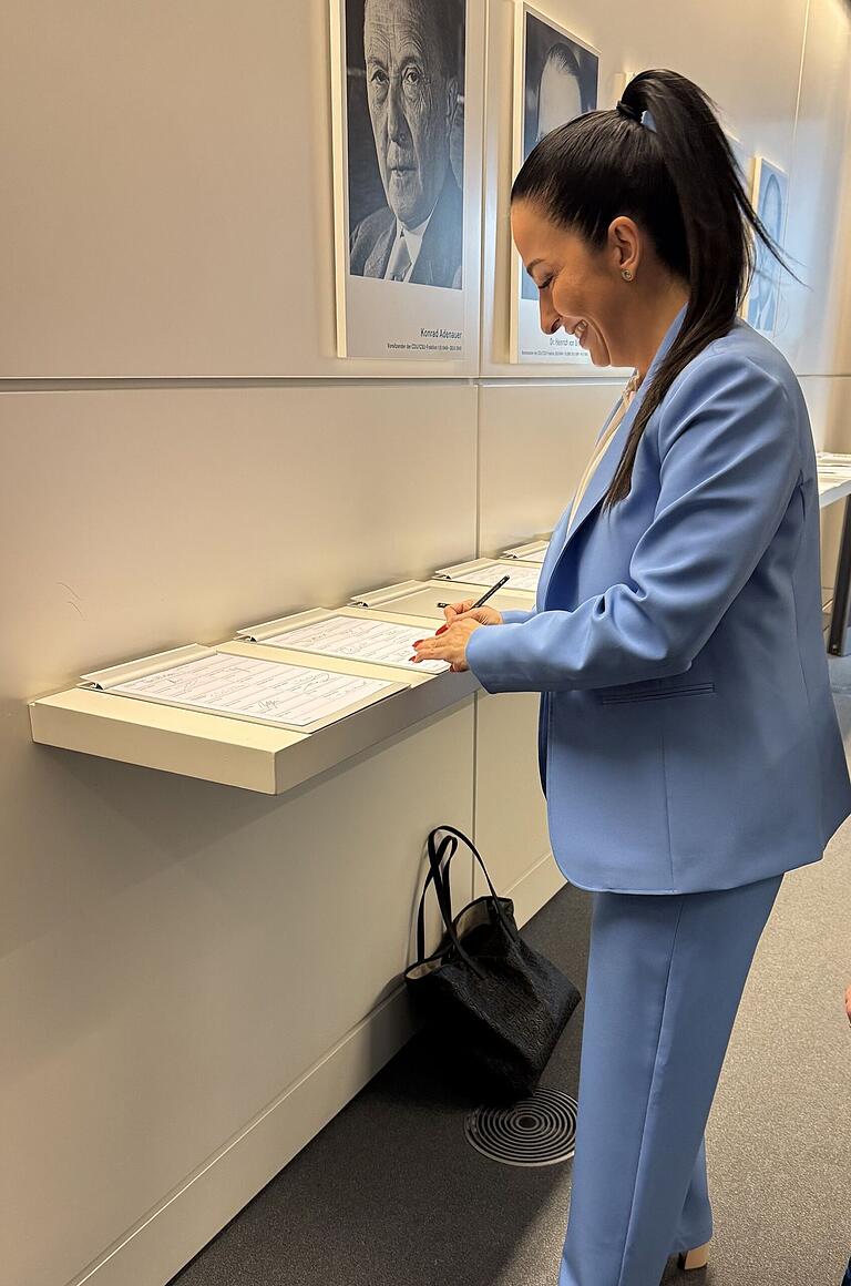 Hülya Düber (CSU) trägt sich unter dem Porträtfoto von Konrad Adenauer in die Anwesenheitsliste des Bundestags ein. Hülya Düber (CSU) trägt sich unter dem Porträtfoto von Konrad Adenauer in die Anwesenheitsliste des Bundestags ein.