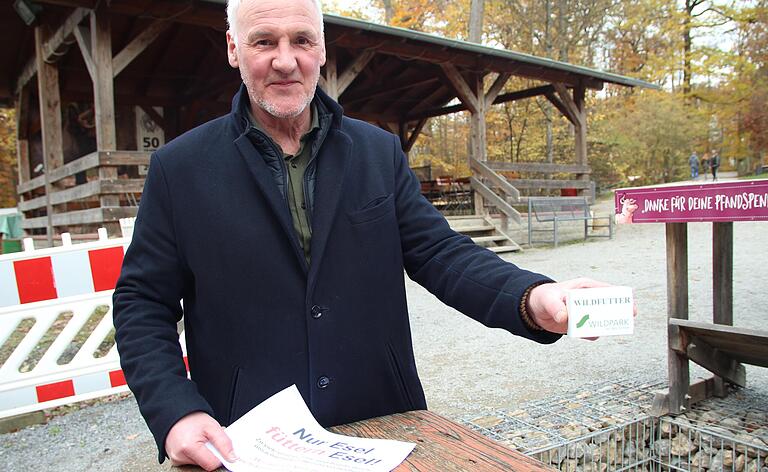 Wildparkleiter Thomas Leier mit Verbotsschildern und einem Futterpäckchen, das es im Wildpark an Automaten zu kaufen gibt.&nbsp;