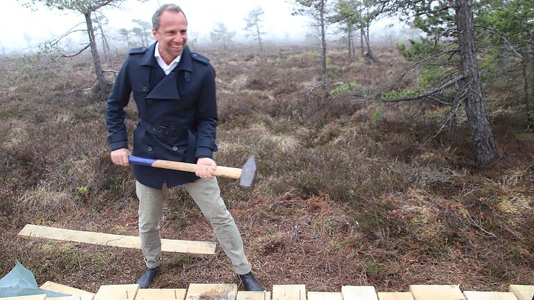 Spontane Aktion: Bayerns Umweltminister Thorsten Glauber wollte seinen Teil zum neuen Bohlensteg im Schwarzen Moor beitragen und griff zum Hammer.