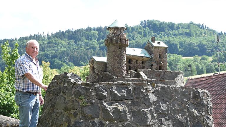 Während sich die Osterburg hinter den Bäumen auf der Anhöhe oberhalb von Frankenheim versteckt, führt Dorfchronist Anton Enders zu einem Modell neben der Dorfkirche.