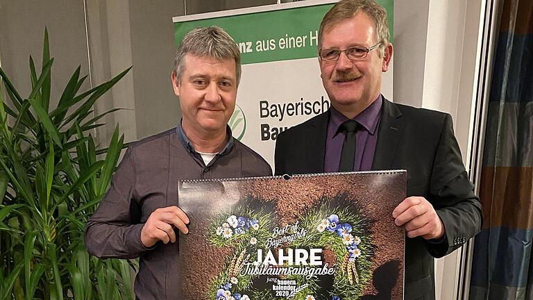Kreisobmann Reinhard Wolz übergibt die Jubiläumsausgabe des Jungbauernkalender an Thomas Wolf aus Eußenheim.
