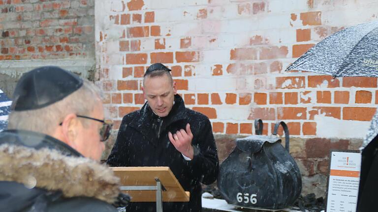 Bürgermeister Mario Götz bei seiner Ansprache. Im Hintergrund ist der künstlerisch umgesetzte Rucksack der Jüdin Regina Berney zu sehen.       -  Bürgermeister Mario Götz bei seiner Ansprache. Im Hintergrund ist der künstlerisch umgesetzte Rucksack der Jüdin Regina Berney zu sehen.