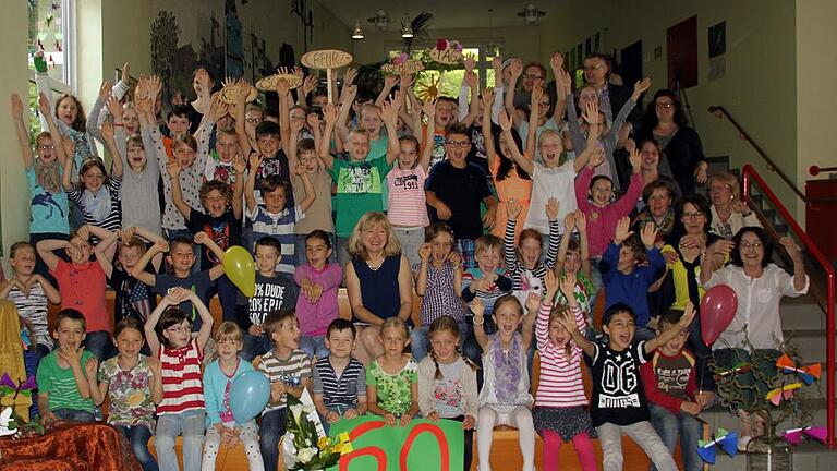 Rektorin belohnt Schüler mit Hausaufgaben-Freiheit       -  (dfi)   31,5 Millionen Minuten &ndash; so alt war Ruth Beckmann (Mitte), die Leiterin der Erlenbacher Grundschule, als sie vergangene Woche Geburtstag feierte. &bdquo;Dagegen sind 60 Jahre eine klitzekleine Zahl&ldquo;, beruhigte sie ihre Stellvertreterin Beate Busch. Denn sie weiß, dass die Rektorin um ihr Alter gerne ein Geheimnis macht. Dass Zeit relativ ist, das bewies die Klasse 1/2 Beckmann bei der Geburtstagsfeier. Die Kinder zählten auf, was jetzt &ndash; während der Feier in der Aula &ndash; noch so alles rund um den Globus passiert: In China kriecht ein Regenwurm zwei Zentimeter, in Prag hat jemand Ziegenpeter. . . Glückwünsche überbrachten auch die anderen Klassen mit einem Gedicht und musikalischen Beiträgen, die Andreas Eyrich auf der Gitarre begleitete. Zum Gratulieren fanden sich neben den Schülern und Lehrerinnen auch Corinna Fischer und Simone Müller, die Vorsitzenden des Elternbeirats, sowie ehemalige Lehrkräfte und Pfarrer Matthias Wolpert ein. Als die Drittklässler mit ihrem Beitrag &bdquo;Ich schenk' dir einen Regenbogen&ldquo; fertig waren und das Geburtstagskind nicht nur gemalte Bilder, Luftballons und sogar eine Torte in der Hand hielt, war Beckmann sichtlich gerührt: &bdquo;Ich bin sprachlos &ndash; und das kommt sehr, sehr selten vor.&ldquo; Sie belohnte ihre Schüler mit einem Eis und dem Versprechen: &bdquo;Heute gibt es für alle hausaufgabenfrei!&ldquo;
