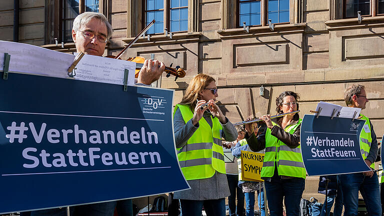 Die Deutsche Orchestervereinigung fordert einen maßgeschneiderten Tarifvertrag für die Staatsbad Philharmonie und veranstaltet am Sonntag 10.10.21 am Rathausplatz in Bad Kissingen einen Musiker-Flashmob für Kissinger Orchester. Rund 50 Musiker aus ganz Bayern solidarisieren sich und nehmen mit gelben Warnwesten teil.