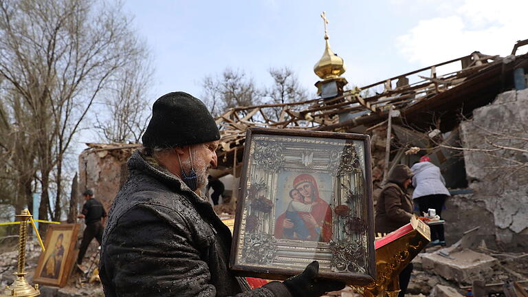 Ukraine-Krieg - Region Saporischschja.jpeg       -  16.04.2023, Ukraine, Komyschuwacha: Ein Priester hält eine geborgene Ikone, während weitere Menschen Trümmer wegräumen, nachdem eine russische Rakete in der Osternacht eine orthodoxe Kirche zerstört hat. Ungeachtet des orthodoxen Osterfests halten die Kämpfe in der von Russland angegriffenen Ukraine an. Foto: Kateryna Klochko/AP/dpa +++ dpa-Bildfunk +++